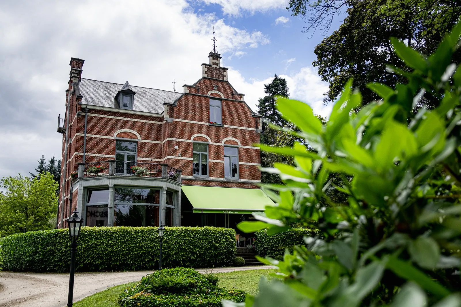 Het herenhuis van Villa San Martino met groene luifel, omgeven door tuin en hagen.